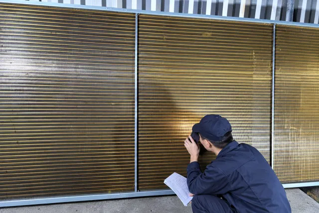 inspector checking a coated coil against the specification sheet