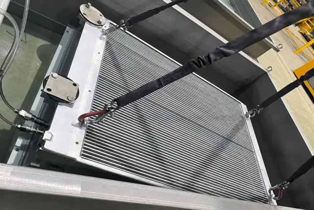 finned heat exchanger suspended on lifting slings in the dip tank