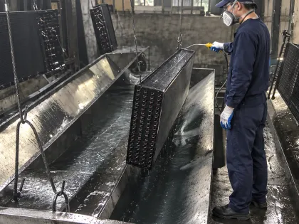 operator clearing a freshly coated coil with an air gun